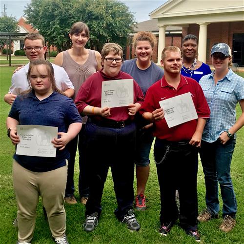 Four teens stand with their principal and riding instructors 